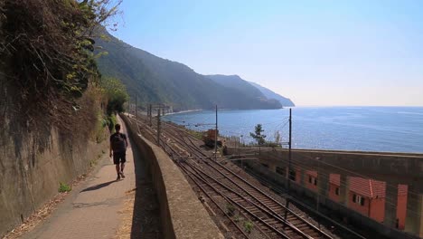 Man-Walks-On-Promenade-Next-To-Coastal-Railway-In-Cinque-Terre,-Italy