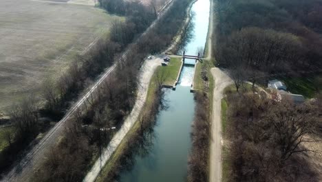 Vista-Aérea-De-Drones-Del-Canal-Hennepin-Y-El-Sendero-De-La-Avenida-Con-Campos-Vacíos-En-La-Distancia-A-Principios-De-La-Primavera-Cerca-De-Colona-Illinois