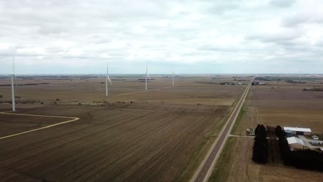 Aerial-view-of-a-farm-yard,-fields-and-wind-turbines-that-are-turned-off-on-a-cloudy-spring-day-in-south-central-Nebraska