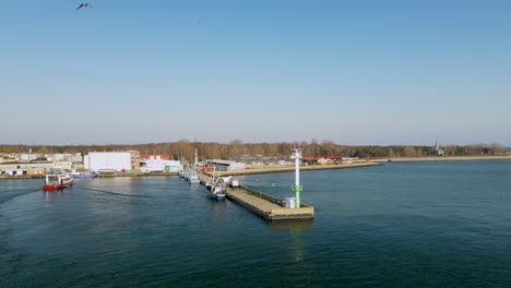 Rotes-Fischerboot-Betritt-Den-Hafen-Auf-Hel,-Klares-Blaues-Wasser-Und-Möwenflug-Auf-Klarem-Himmel,-Zeitlupe