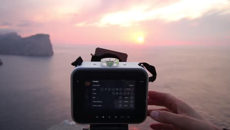 Videographer-adjust-camera-settings-and-ND-exposure-filter-shooting-scenic-sea-landscape-at-Dusk