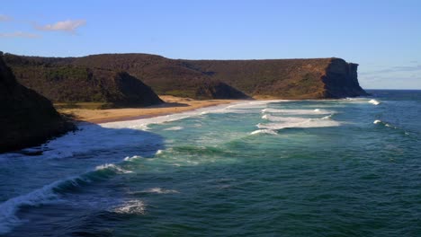 Sea-Waves-Onto-Shore-Of-Garie-Beach-Overlooking-Garie-North-Head-In-Royal-National-Park,-NSW-Australia---Aerial-Drone-Shot