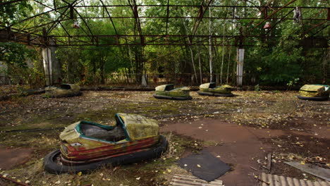 Abandoned-and-rusty-bump-cars-in-Pripyat-amusement-park,-zoom-out-view