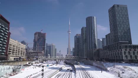 Toronto-downtown,-CN-Tower,-condo-buildings,-train-railway-transportation-during-winter