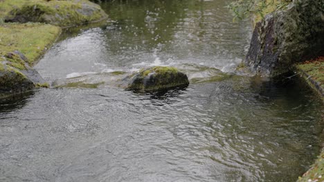 Ruhiger-Wasserfluss,-Der-Im-Frühjahr-Neben-Felsen-In-Einem-Japanischen-Garten-Fließt