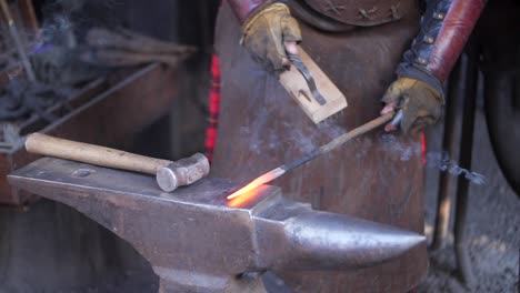 A-blacksmith-brushing-his-work-on-an-anvil-in-his-forge,-workshop,-close-up