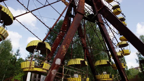 Rustic-Ferris-wheel-with-yellow-baskets-in-Pripyat,-tilting-up-view