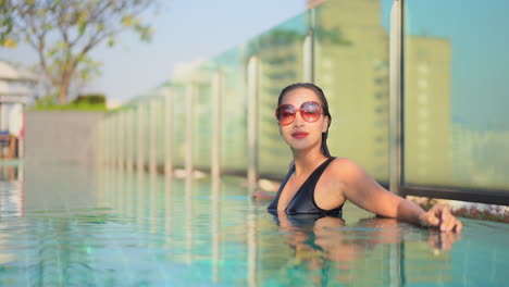 Junge-Asiatische-Frau-Mit-Vintage-Sonnenbrille,-Die-Sich-Im-Dachpool-Des-Hotels-Entspannt