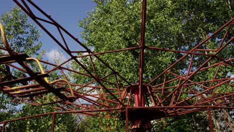 Abandoned-swing-ride-spinning-in-wind-in-Pripyat,-zoom-out-view