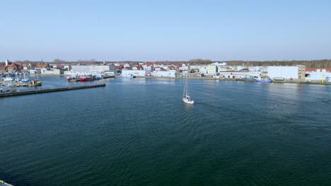 Weißes-Segelboot-Betritt-Den-Hafen-Auf-Dem-Ruhigen-Wasser-Der-Stadt-Hel-Auf-Puck-Bay,-Luftzeitlupe