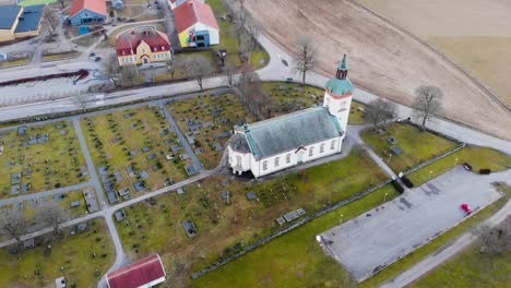 Aerial-View-Of-White-Church-Building-On-Lush-Green-Grass-With-Leafless-Trees-Near-The-Street