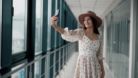 Fröhliches-Schönes-Mädchen-In-Einem-Brett-Und-Hut-Macht-Ein-Selfie-Auf-Einem-Smartphone