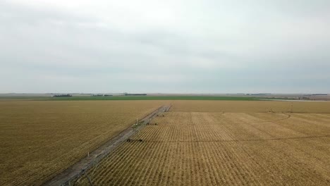 Vista-Aérea-De-Un-Campo-De-Maíz-A-Principios-De-La-Primavera-Y-Un-Camino-De-Ripio-De-Mantenimiento-Mínimo-En-La-Zona-Rural-De-Nebraska,-EE.UU.
