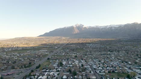 Aerial-View-Of-City-Of-Ogden-In-Utah-With-Rugged-Snow-capped-Mountain-Range-In-Background-On-A-Sunny-Morning