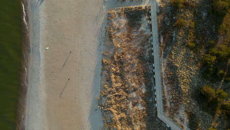 Luftaufnahmen-Von-Oben-Nach-Unten-Vom-Sandstrand-Mit-Menschen,-Die-An-Windigen-Tagen-In-Hel-In-Polen-Drachen-Steigen-Lassen