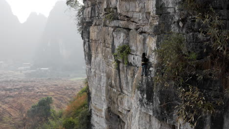 Female-rock-climber-ascending-The-Egg-rock-face,-Yangshuo-China,-4K-aerial-view