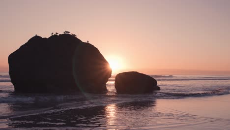 Otherwordly-lens-flare-from-behind-rock-boulders-during-low-tide-at-beach