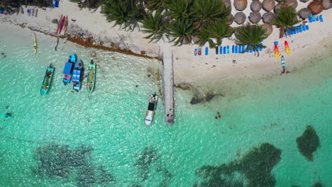 Cinematic-downward-angle-drone-shot-starting-on-a-pier-then-rising-to-reveal-the-resort-beach-at-Mahahual-Mexico