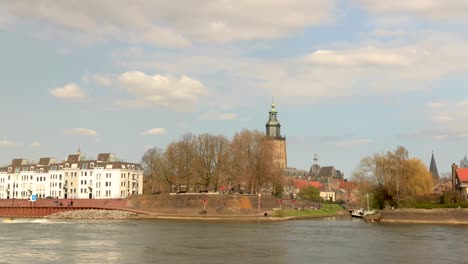 Countenance-movement-in-time-lapse-of-pleasure-boats-and-traffic-along-and-on-the-cityscape-boulevard-of-Zutphen-with-Walburgiskerk-cathedral-towering-behind-and-reinforced-wall-in-foreground