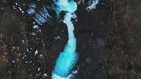 Luftaufnahme-Des-Majestätischen-Isländischen-Wasserfallflusses-Zwischen-Felsiger-Landschaft-Und-Bergen-Im-Hintergrund