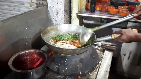 Street-food-man-is-cooking-pad-noodle-with-egg-at-a-night-food-market-in-India,-Quick-cooking-Chinese-noodles-close-up,-Cooking-homemade-quick-pasta-soup