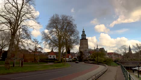Time-lapse-of-cars-on-meandering-town-road-with-Walburgiskerk-cathedral-towering-behind-against-a-blue-sky-with-clouds-developing-above