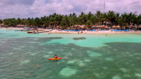 Drone-shot-of-person-kayaking-in-the-clear-ocean-water-at-the-coastal-resort-town-of-Mahahual-Mexico