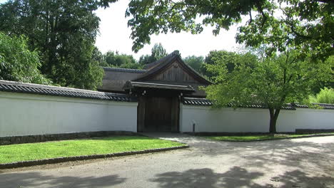 Long-shot-of-the-roofed-hinoki-wood-gate-and-tiled-wall-at-the-entrance-of-a-Japanese-house