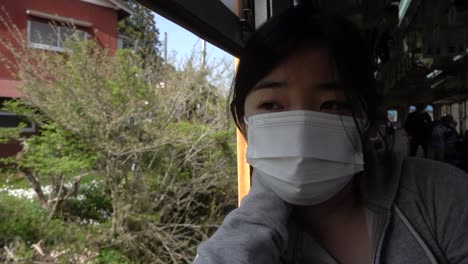 Junges-Japanisches-Mädchen-Mit-Gesichtsmaske-Gegen-Korona,-Das-Aus-Dem-Fahrenden-Zug-Schaut