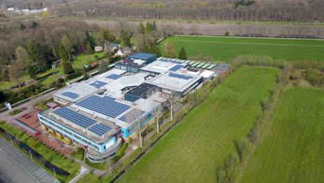Cinematic-aerial-of-large-high-school-with-solar-panels-on-rooftop