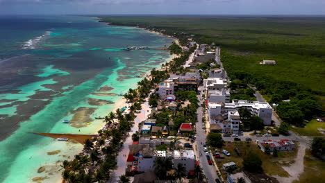 Cinematic-drone-shot-of-the-coastal-resort-town-of-Mahahual-Mexico,-beautiful-clear-ocean-water