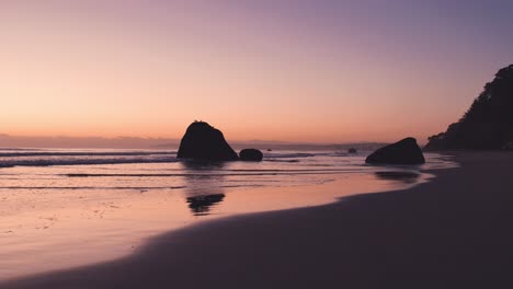 Magical-morning-sunrise-with-vibrant-colors-at-low-tide-beach-with-boulders