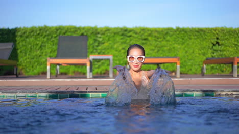 Fröhliches,-Schönes-Asiatisches-Mädchen,-Das-Im-Resort-Pool-Badet,-Spielt-Mit-Wasser