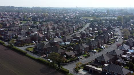 Countryside-housing-estate-aerial-rise-left-view-flying-across-England-farmland-residential-community-homes