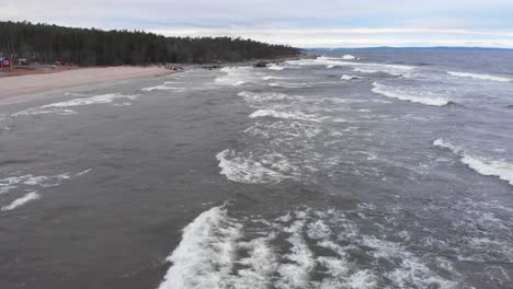 Cold-foamy-waves-of-Baltic-sea-coming-into-Swedish-coastline---Aerial