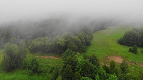 Fog-above-woods-and-meadow-of-Bieszczady-Mountains-on-rainy-day,-aerial-view