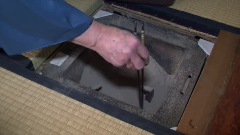 Japanese-tea-master-uses-chopsticks-to-prepare-ashes-inside-Japanese-shichirin-charcoal-stove