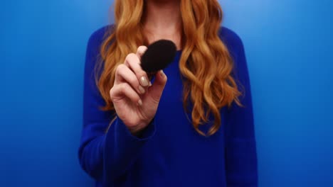 Beautiful-ginger-redhead-young-girl-wearing-blue-sweater-posing-isolated-on-blue-color-background-in-studio