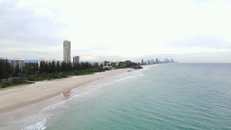 Blue-Water-Of-Burleigh-Beach-With-A-View-Of-Beachfront-Apartment-Buildings-And-Rocky-Cliff-In-Gold-Coast-City,-Australia