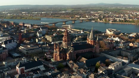 Verlassen-Der-Mainzer-Domkirche-Drohnenaufnahmen-An-Einem-Warmen-Frühlingstag,-Die-Den-Blauen-Fluss-Im-Hintergrund-Zeigen