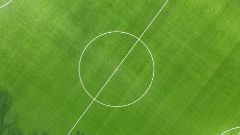 Top-down-aerial-of-center-spot-of-soccer-field---drone-lifting-up-and-spinning