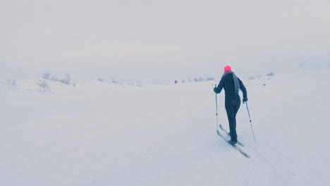 Female-cross-country-skier-in-a-black-body-suit-and-pink-beanie-exercising-alone