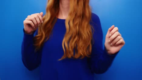 Cheerful-ginger-redhead-young-girl-wearing-blue-sweater-dancing-isolated-on-blue-color-background-in-studio