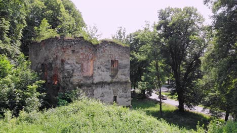Ancient-tower-ruin-in-overgrown-park-aerial-view,-Dabrowka-Starzenska,-Poland