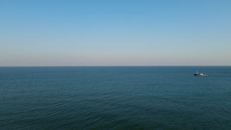 Aerial-wide-shot-of-Ship-cruising-on-endless-Ocean-during-beautiful-blue-sky-and-sunlight