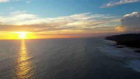 Antenne-Des-Wunderschönen-Sonnenuntergangs,-Der-Sich-Im-Wasser-Mit-Wellen-Und-Surfern-Im-Pazifischen-Ozean-In-Tamarindo,-Costa-Rica,-Widerspiegelt