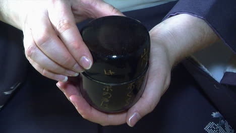 The-cap-of-a-chazutsu-tea-canister-is-removed-to-show-the-green-Matcha-tea-inside