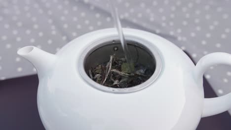 Heißes-Wasser,-Das-Auf-Frische-Teeblätter-In-Einer-Teekanne-Aus-Porzellan-Gepumpt-Wird