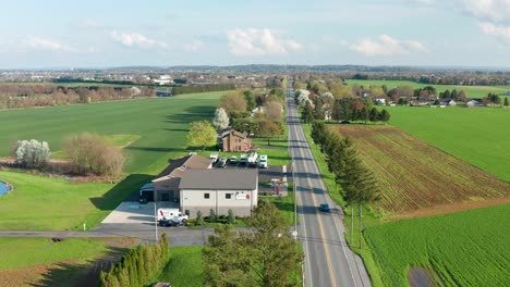 Aerial-of-long-straight-road-in-rural-America,-USA-during-spring