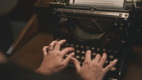 Cinematic-over-the-shoulder-shot-of-woman-typing-on-vintage-typewriter